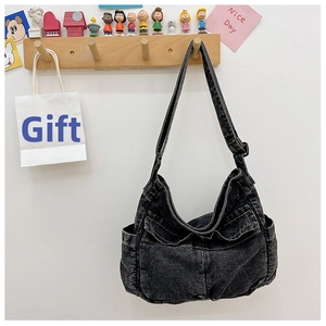 Detail of vintage black denim crossbody bag featuring multi-pocket design and adjustable strap