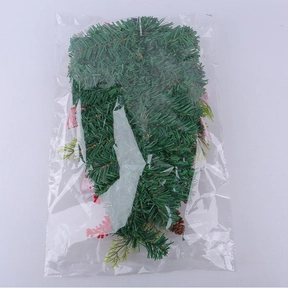 Detail of green artificial pine needle garland with red berries in packaging