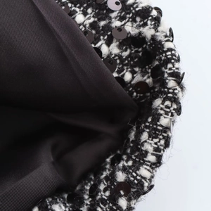 Macro shot of black and white tweed fabric with sequins and silky inner lining