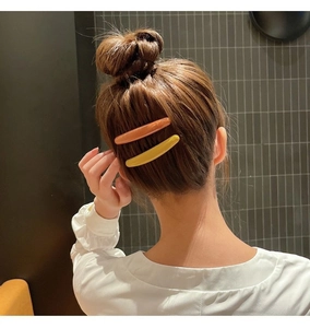 Detail of yellow and orange hair combs securing loose strands on a female model