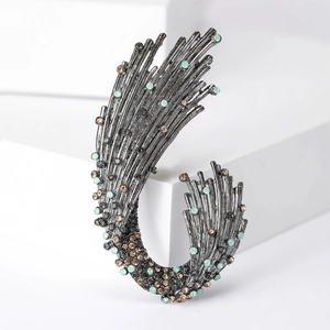 Detailed macro view of retro alloy wave brooch with dark and gold rhinestones inlay