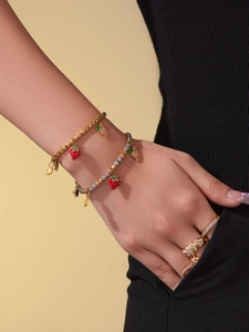 Detail of beaded fruit charm bracelets with strawberry and pineapple pendants for women