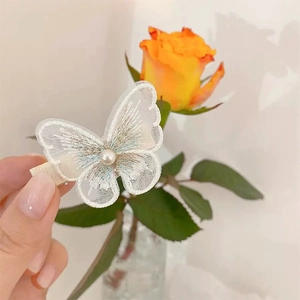 Close-up of white mesh butterfly hair clip with pearl detail and lace embroidery accents