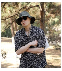 Outdoor camouflage bucket hat with adjustable wind cord shown in a sunny forest setting