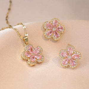 Elegantes goldenes Blumen Schmuckset mit rosa Steinen auf Seide für Frauen