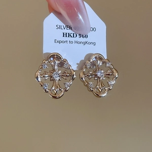 Macro shot of gold-plated silver cross stud earrings with sparkling zircon stones