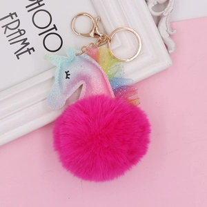 Close-up of glittery unicorn plush keychain with lace trim on a pink background
