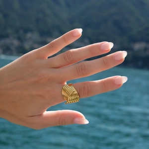 Modischer 18k vergoldeter Edelstahlring mit Spiralmuster vor Meereshintergrund