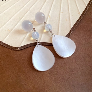 Detail of bamboo hoop earrings with purple beads and white shell teardrop pendants