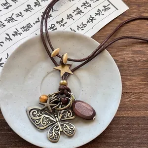 Détail de pendentifs vintage en bronze papillon et étoile de mer sur collier en bois