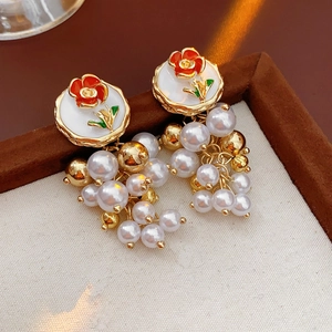 Détail des boucles d'oreilles vintage fleurs émaillées et pampilles de perles