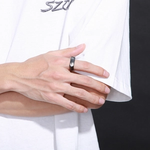 Primo piano di un anello geometrico nero opaco sulla mano con dettagli d'ombra
