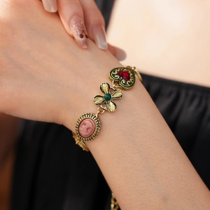 Gros plan d'un bracelet doré vintage avec camée, cœur rouge et breloques trèfles