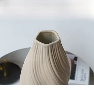 Détail du vase en céramique plissé avec une finition mate et une texture ondulée