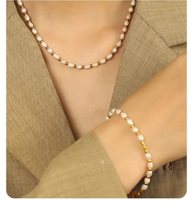 Baroque freshwater pearl and gold bead jewelry set worn on a suit sleeve