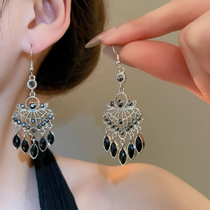 Detailed view of silver vintage tassel earrings with black gemstones on a model