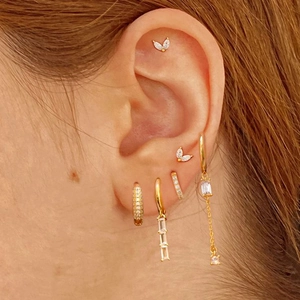 Close-up of gold ear set featuring zircon butterfly studs and vertical pendant drops