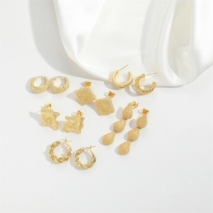 Detail view of various gold geometric earrings set on elegant white silk fabric