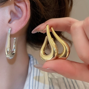 Polished metal C-shape stud earrings in gold and silver finish on female model