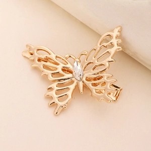 Close-up of golden hollow butterfly hair clip with a sparkling central rhinestone detail
