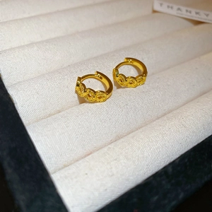 Close-up of 18k gold plated round earrings with intricate engraved texture in a velvet box