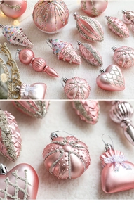 Pink Christmas ornaments with pearl finish and glitter details on white fur background