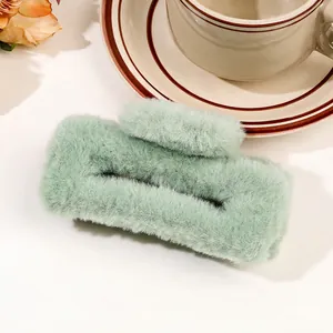 Macro shot of mint green plush hair claw clip with soft faux fur texture on a lifestyle setup