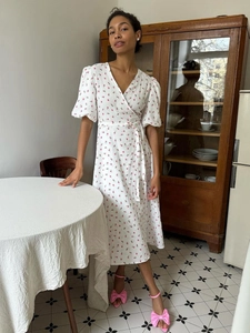 Close-up of floral cotton wrap dress featuring puff sleeves and tie waist detail