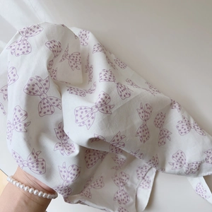Détail du sac en coton blanc avec imprimés nœuds violets doux et motifs à pois
