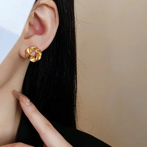 Detailed view of matte gold pleated geometric earring worn for size and texture reference