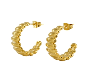 Détail de boucles d'oreilles créoles dorées avec texture côtelée et finition 18 carats