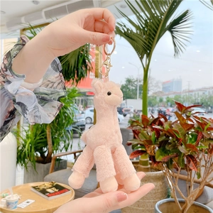 Detailed view of a pink plush alpaca keychain with a golden clasp on a bag