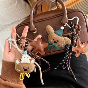 Brown plush bear keychain with party hat, star charm and heart clasp on bag