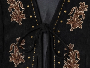 Détail de broderie florale sur gilet en velours noir avec fermeture lacée