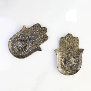 Macro view of the black and gold ceramic Hamsa Hand jewelry tray with mandala details