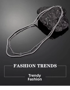 Detail view of double-layered silver chain necklace with ring accents on a black background