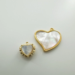 Macro detail of heart-shaped white shell pendants with 18K gold plated beaded edges