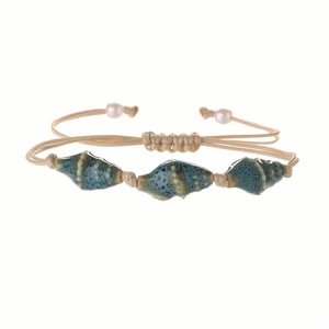 Bohemian woven bracelet with blue ceramic conch beads and white pearls on white background