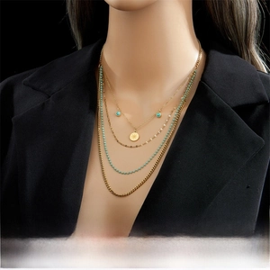Détail du collier doré multicouche avec pendentif soleil et chaîne à perles bleues