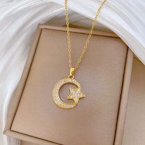 Elegant gold celestial necklace with star and moon cubic zirconia pendants on silk background