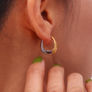 Polished two-tone 18K gold and silver mini pear-shaped hoop earring on female model