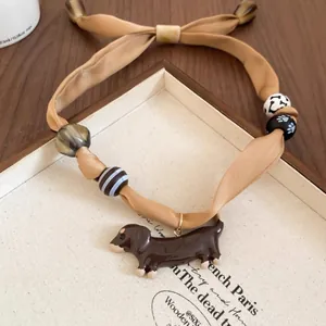 Detailed macro view of khaki silk puppy pendant necklace with decorative wood beads