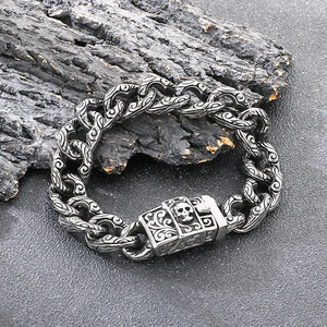 Macro detail of gothic Cuban link bracelet with engraved skull clasp and floral patterns
