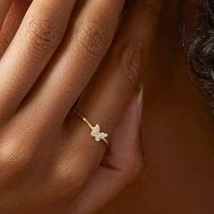 Close-up of golden butterfly ring with sparkling diamonds on a finger