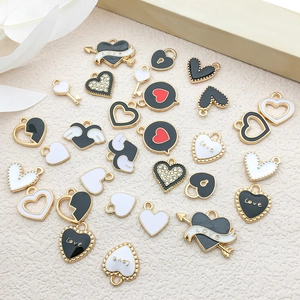 Macro detail of heart and wing alloy pendants with black and white enamel and rhinestones