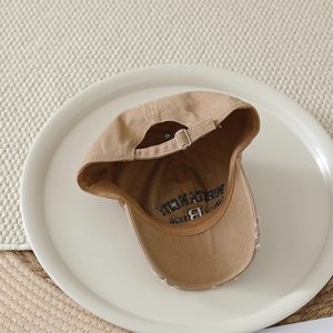 Detail of khaki cotton canvas baseball cap with distressed brim and metal buckle
