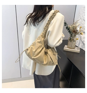 Detail of beige pleated tote bag featuring ruffled shoulder straps and side drawstring cords