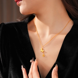 Close-up of gold-plated horse and coin pendant necklace worn by a model in soft light
