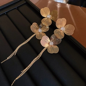 Vue détaillée de boucles d'oreilles fleurs dorées à glands et cristaux sur plateau noir