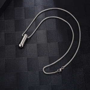 Vue de dessus d'un collier pendentif capsule en acier titane poli sur fond noir texturé